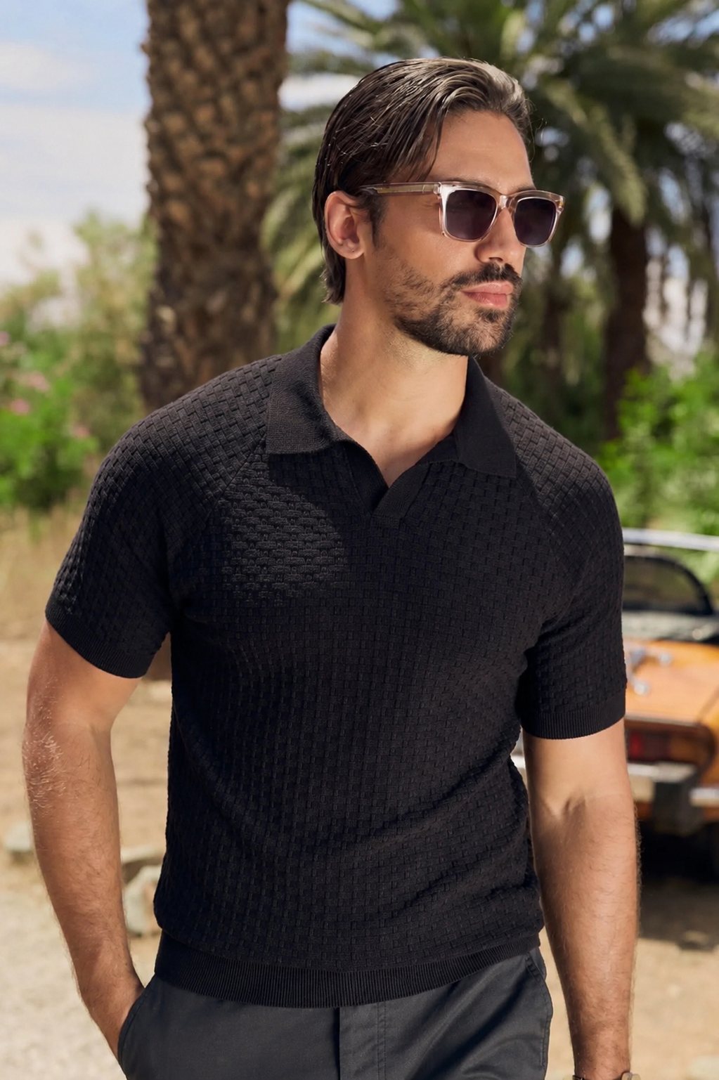 Man in a black knitted polo wearing Somnia Champagne Gold sunglasses