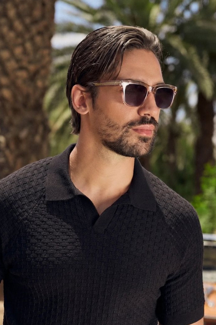 Man in a black knitted polo wearing Somnia Champagne Gold sunglasses