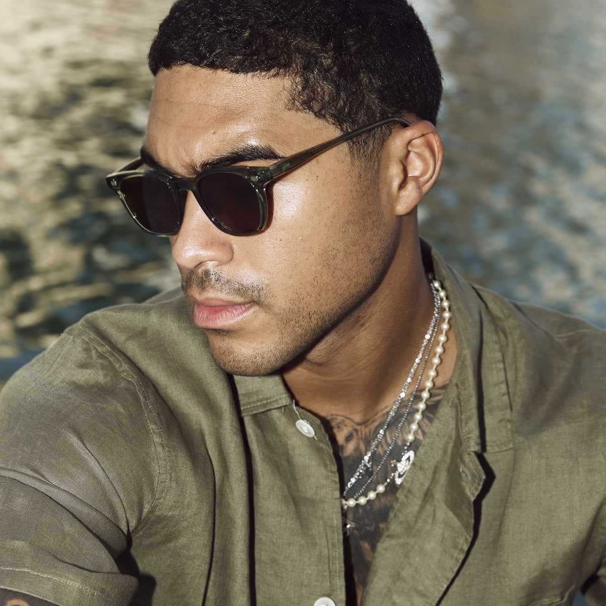 Man wearing Lucid Green/Brown sunglasses by the water