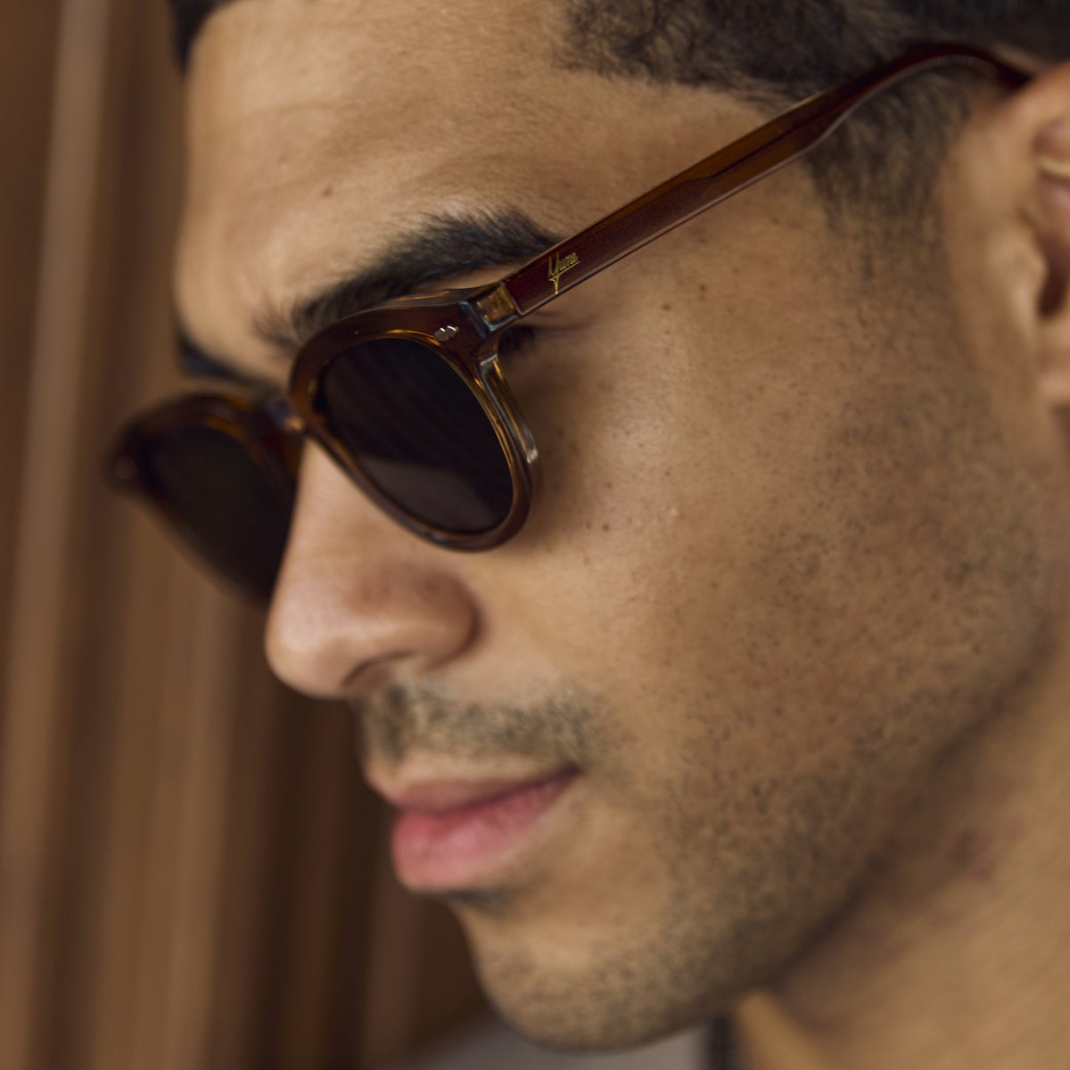 Close-up of a man wearing Noxie Brown/Green round sunglasses