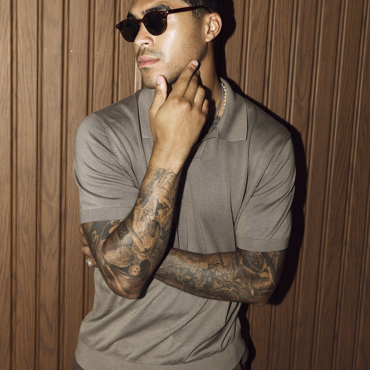Man wearing Noxie Brown/Green sunglasses against a wooden wall