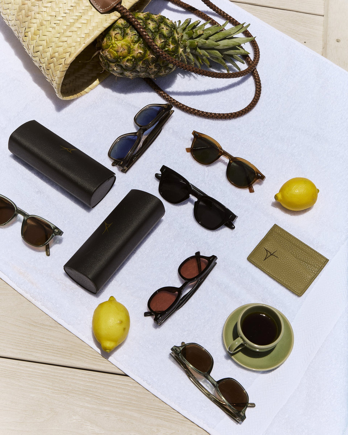 Yume sunglasses, hard cases, lemons and a pineapple on a white cloth