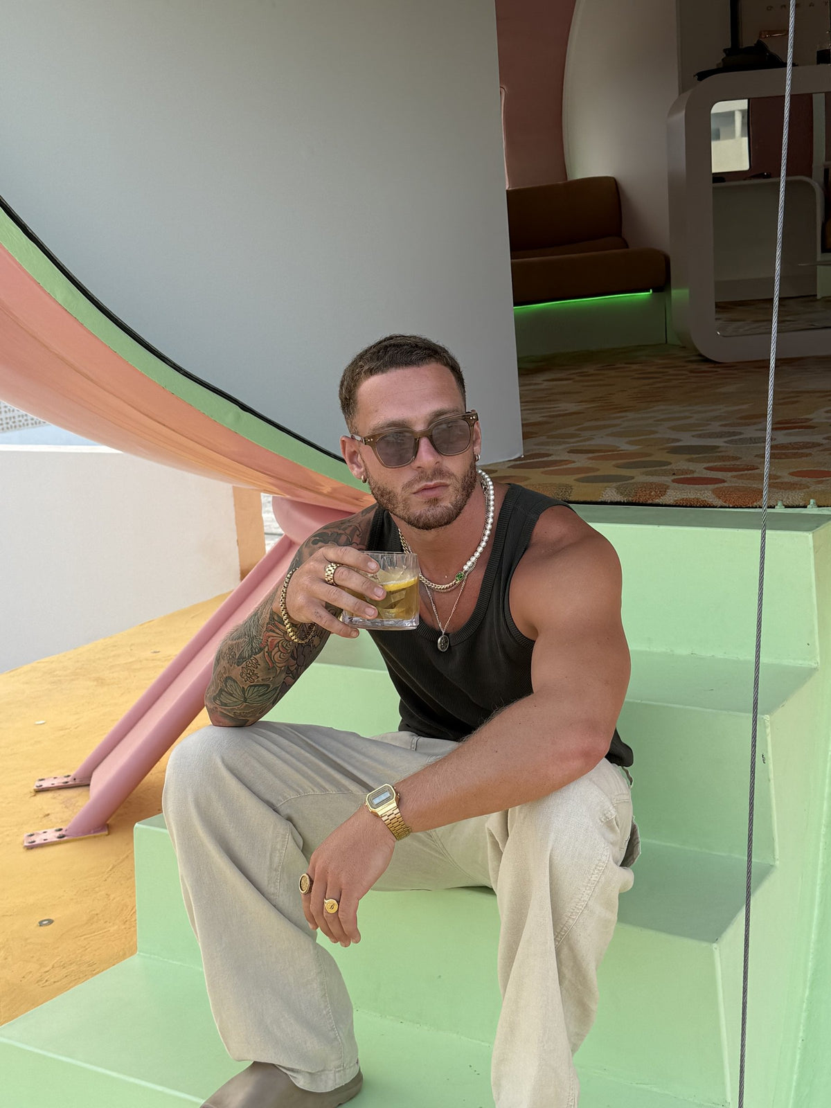 Man in a black vest wearing clear Yume sunglasses on green steps