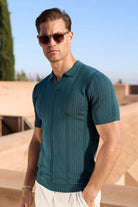 Man in a teal knitted polo wearing Somnia Champagne Gold sunglasses