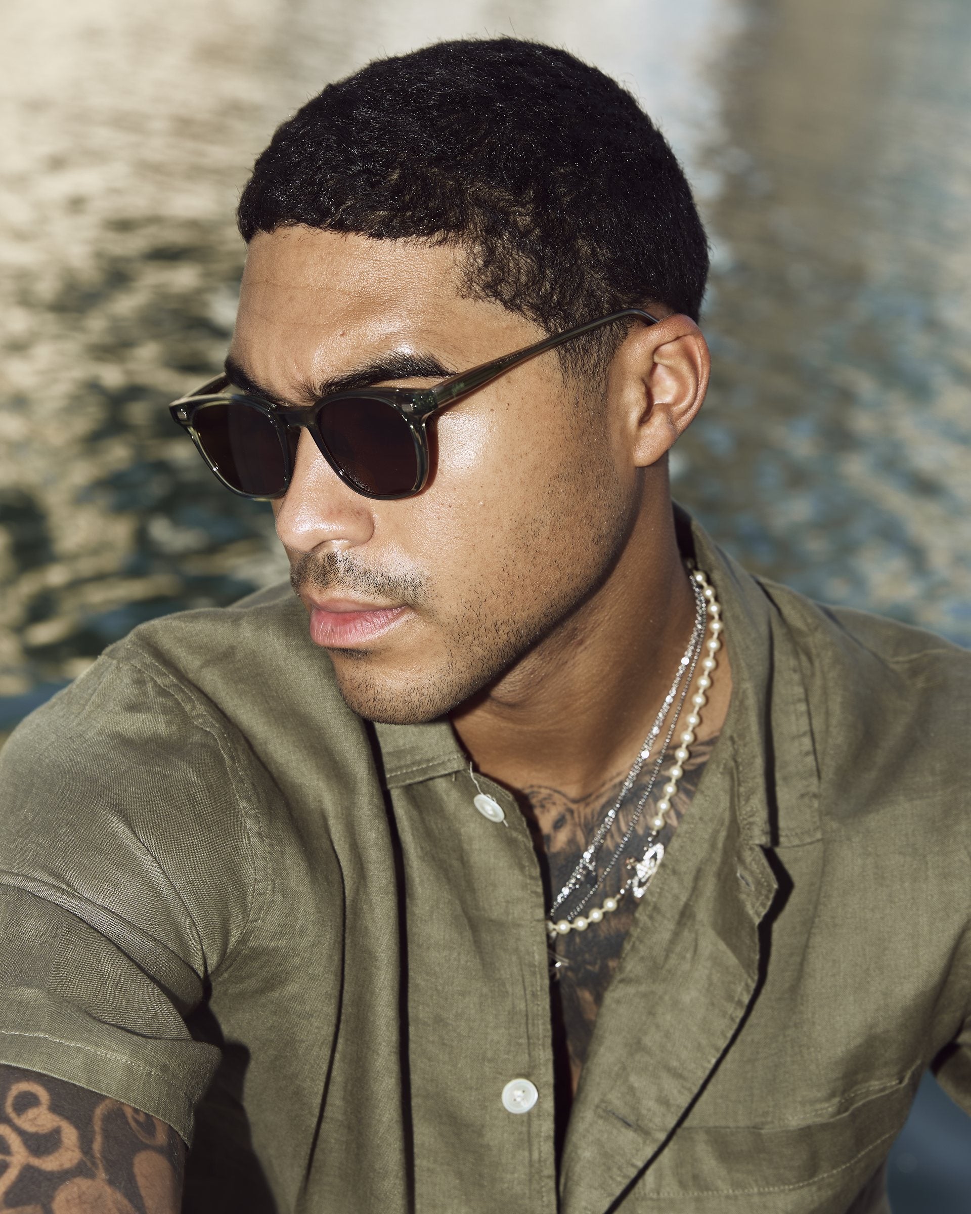 Man wearing Lucid Green/Brown sunglasses by the water