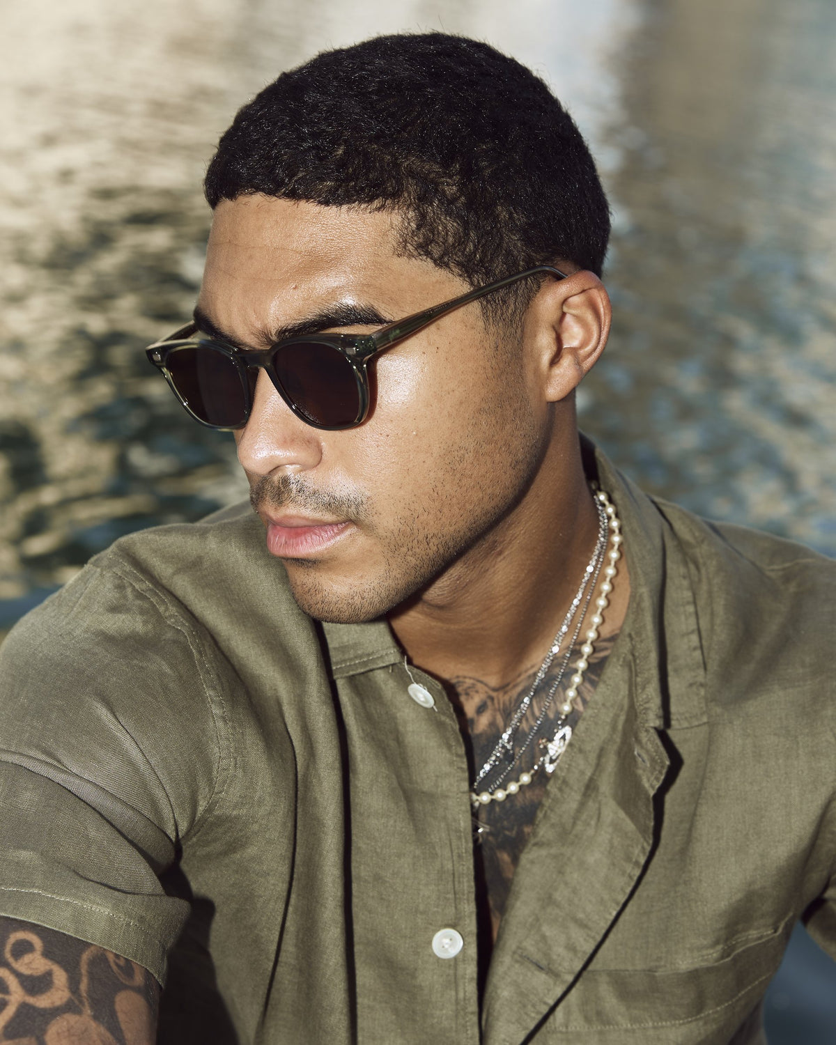 Man wearing Lucid Green/Brown sunglasses by the water